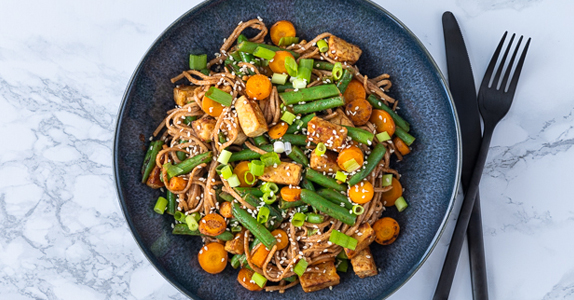 Noedels met tempeh op een bord geserveerd 